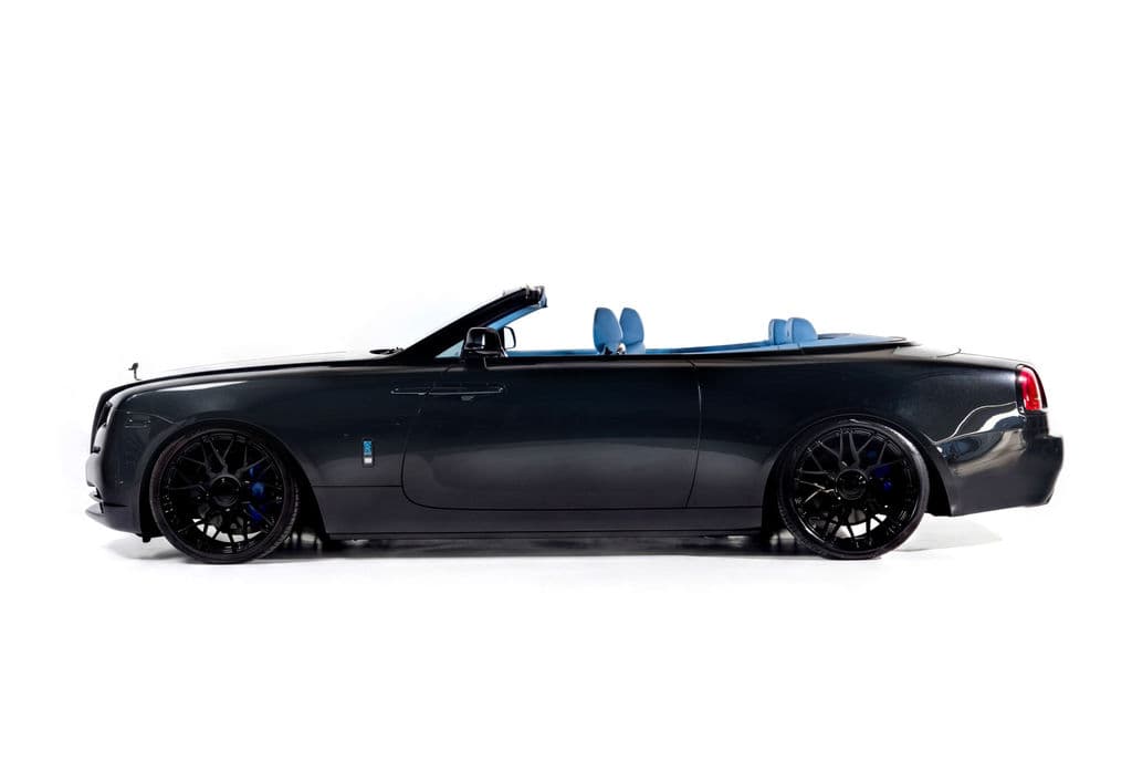 Black Rolls-Royce Dawn convertible with the roof down, in side profile against a white studio sweep